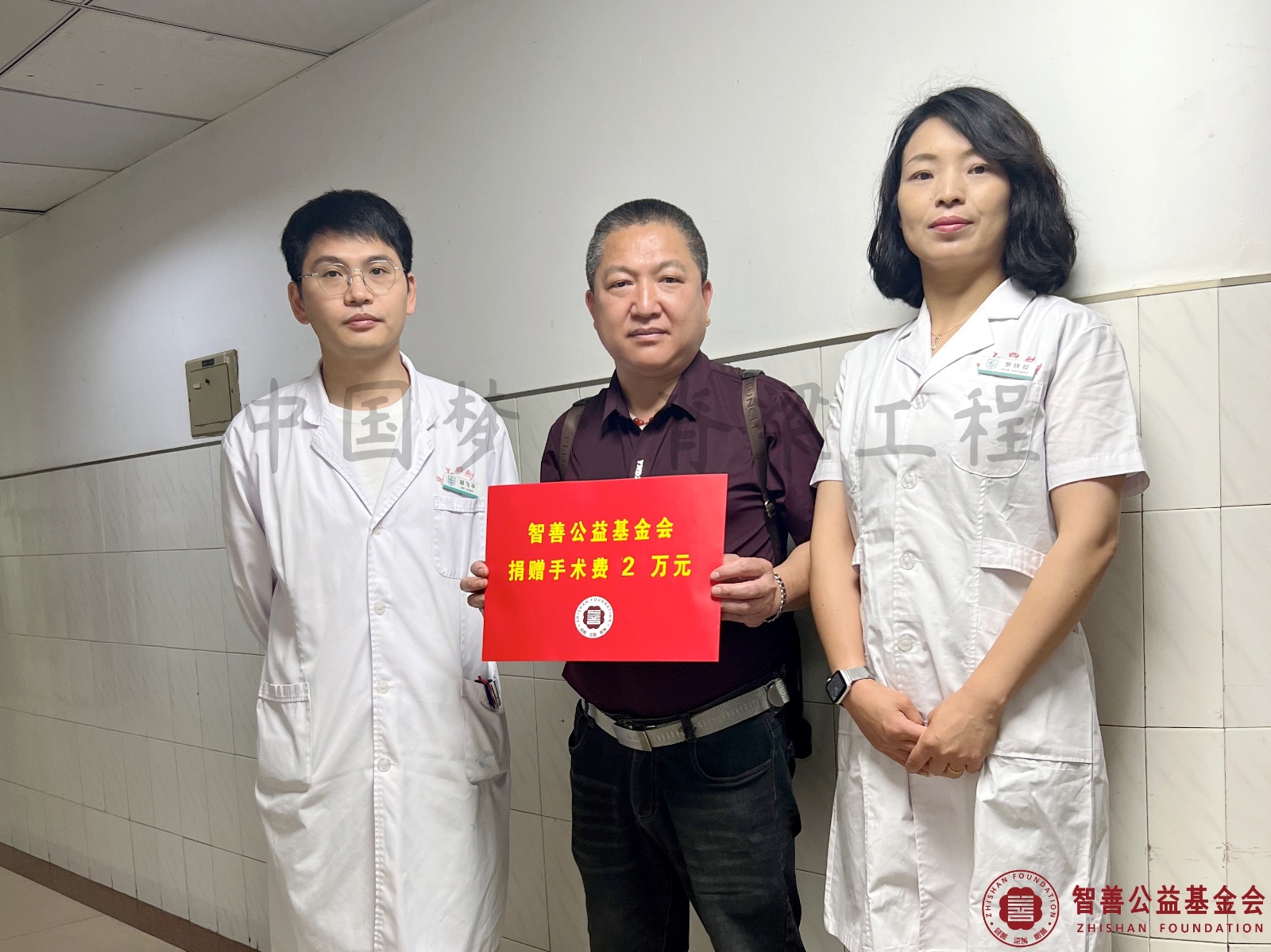 9 南昌大学附属康复医院爱心志愿者罗铁姣（右）、胡飞平主治医师将智善公益基金会捐赠的2万元转交给江西上饶鄱阳县患者小汪（其父代领）.jpg