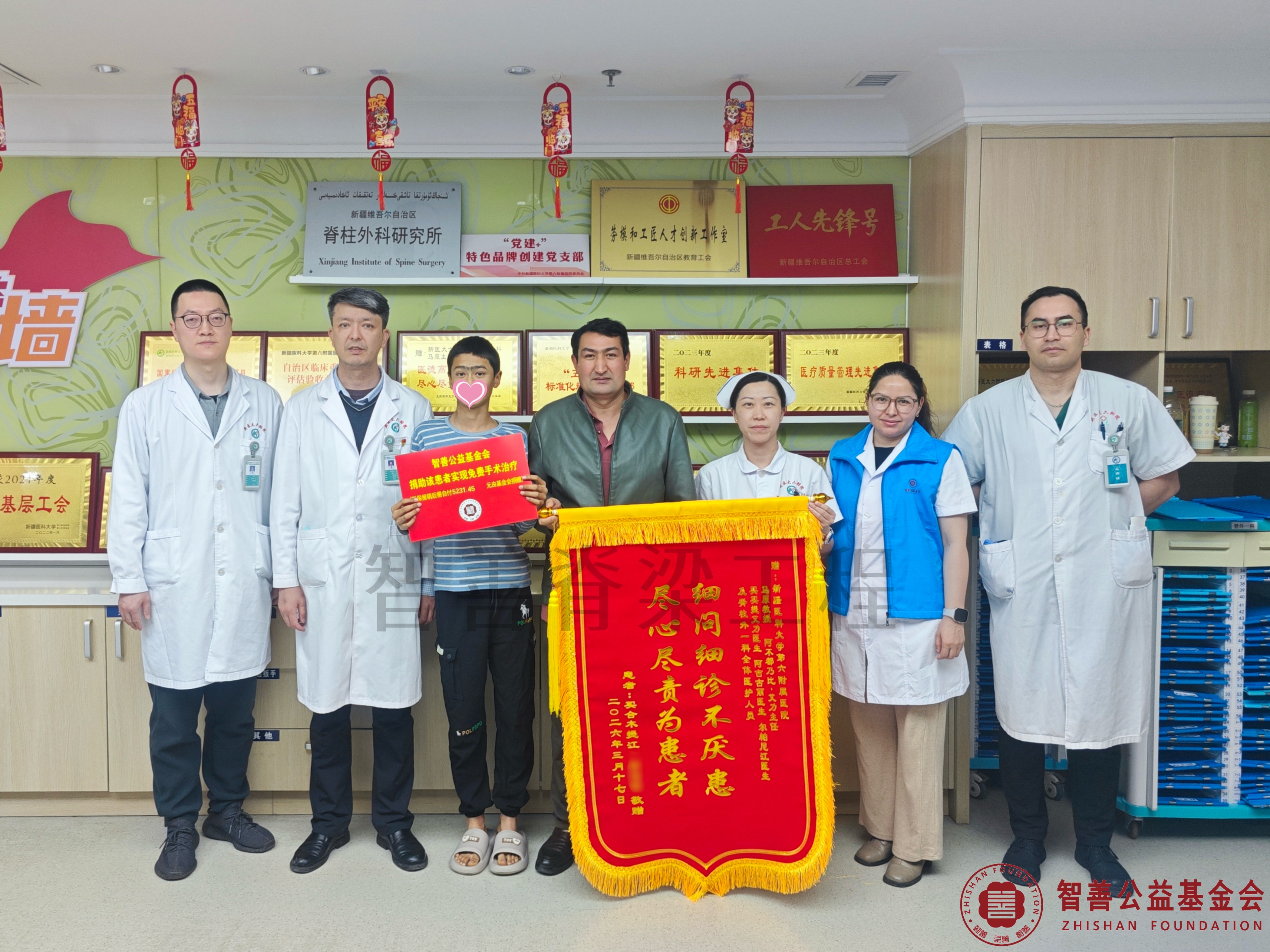 16新疆医科大学第六附属医院阿不都乃比·艾力主任（左二）、（左起）李栎医生、王欢护士长、爱心志愿者阿吉古丽、尔帕尼江医生将智善公益基金会捐赠的5231.45元转交给新疆喀什疏附县患者麦合穆提江（该患者实现免费手术治疗）.jpg