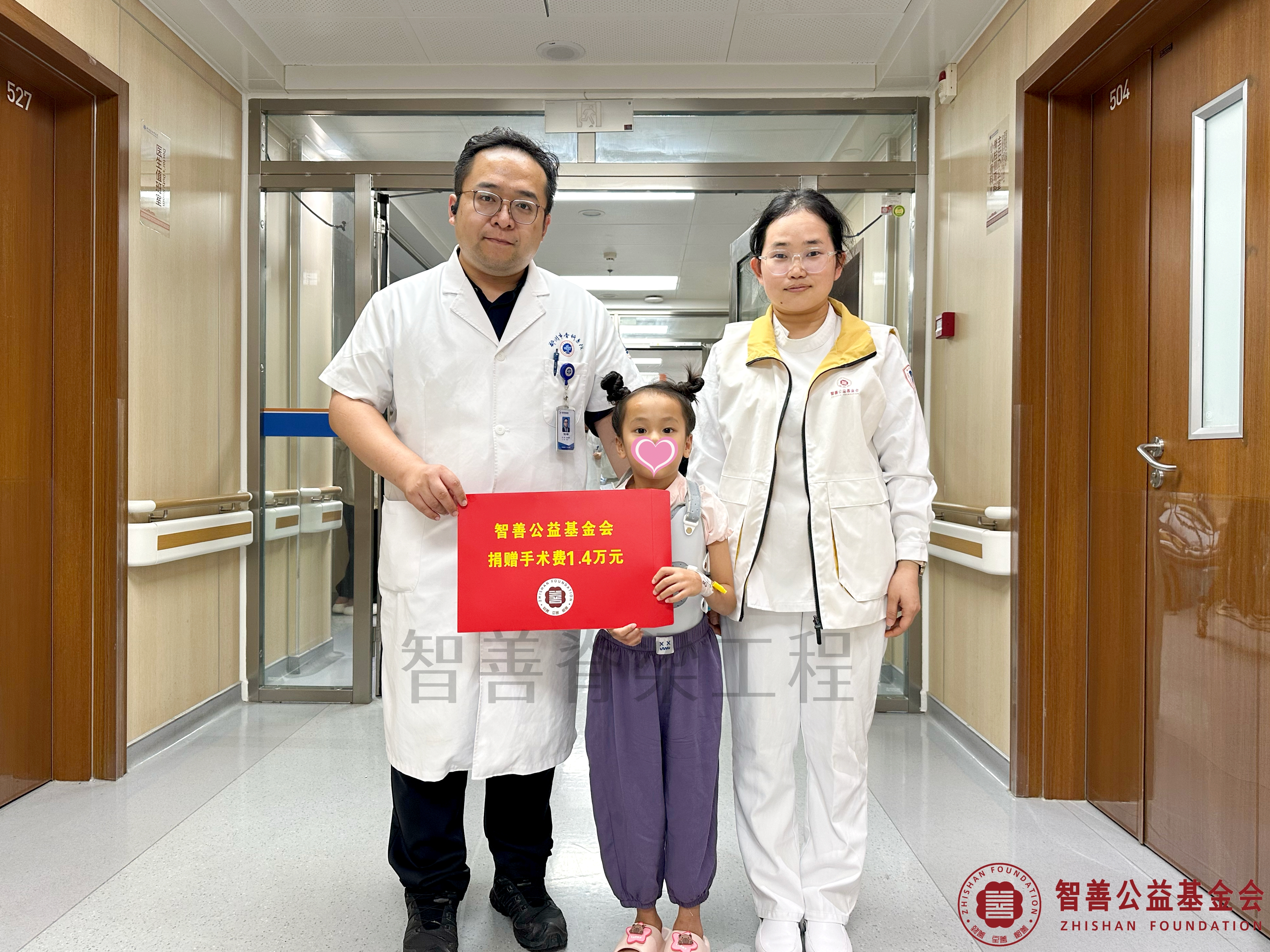 108郑州市骨科医院（左起）刘少峥医生、爱心志愿者孙静娜将智善公益基金会捐赠的1.4万元转交给河南商丘梁园区患者邸梓芮.jpg